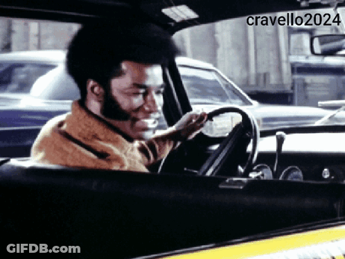A Man Is Smiling While Driving A Car With The Hashtag Cravello2024 GIF