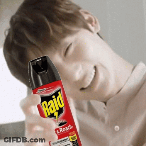 A Man Is Smiling While Holding A Bottle Of Raid Roach Spray GIF