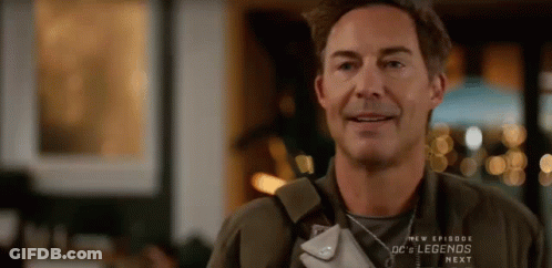 A Man Is Smiling While Holding A Purse In His Hand . GIF