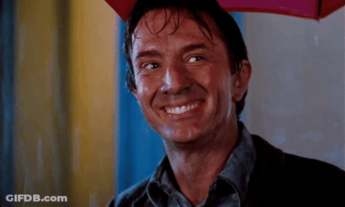 A Man Is Smiling While Holding A Red Umbrella GIF