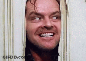 A Man Is Smiling While Looking Through A Doorway . GIF