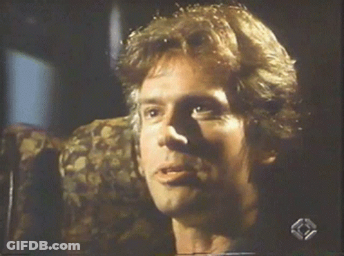 A Man Is Smiling While Sitting In A Chair On A Television Screen GIF