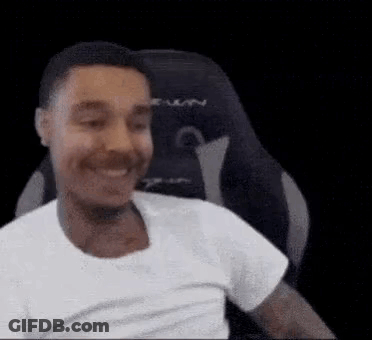 A Man Is Smiling While Sitting In A Gaming Chair . GIF