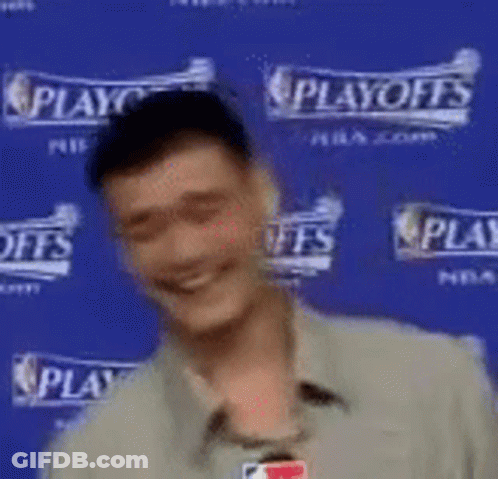 A Man Is Smiling While Standing In Front Of A Blue Wall That Says Playoffs . GIF