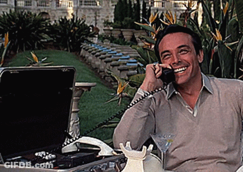 A Man Is Smiling While Talking On A Cell Phone GIF