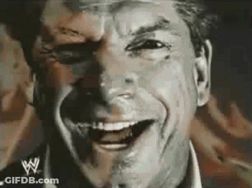 A Man Is Smiling With A Wrestling Logo On His Shirt GIF