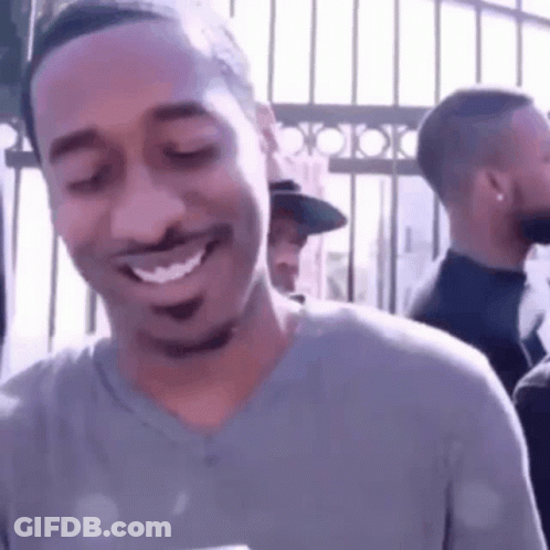 A Man Is Smiling With His Eyes Closed While Standing In Front Of A Crowd . GIF
