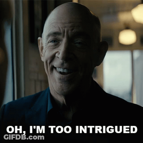 A Man Is Smiling With The Words Oh I 'M Too Intrigued Behind Him GIF