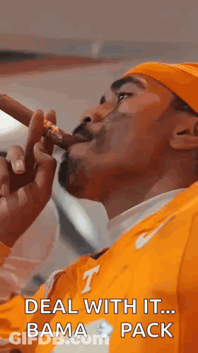 A Man Is Smoking A Cigar And Wearing An Orange Shirt . GIF