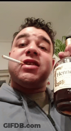 A Man Is Smoking A Cigarette And Holding A Bottle Of Hennessy Cognac GIF