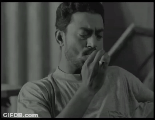 A Man Is Smoking A Cigarette In A Black And White Photo GIF