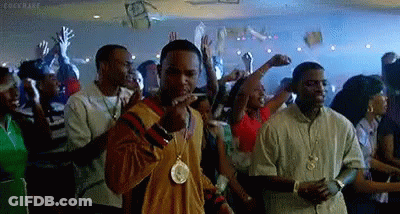 A Man Is Smoking A Cigarette In A Crowd Of People At A Party . GIF