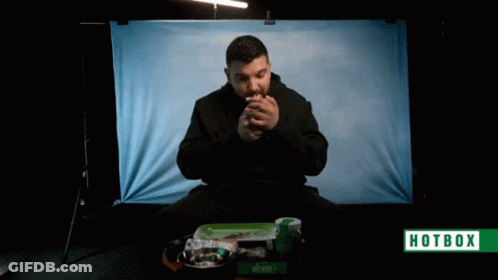 A Man Is Smoking A Cigarette In Front Of A Hotbox Banner GIF