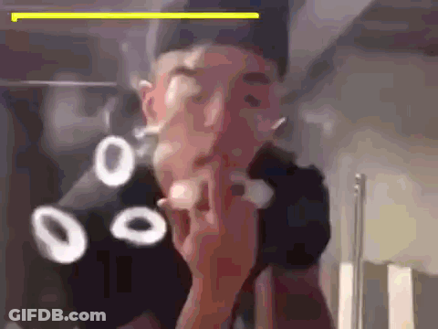 A Man Is Smoking A Cigarette In Front Of A Mirror While Wearing A Black Hat . GIF