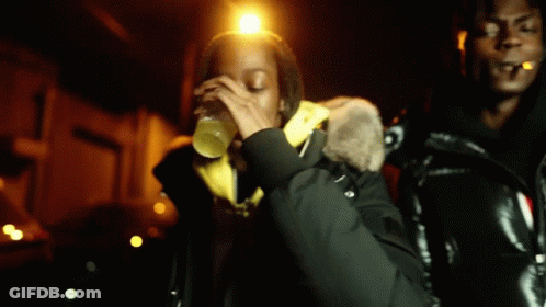 A Man Is Smoking A Cigarette While A Woman Drinks From A Bottle . GIF
