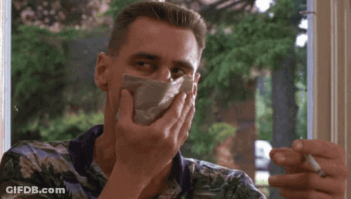 A Man Is Smoking A Cigarette While Covering His Mouth With A Napkin GIF