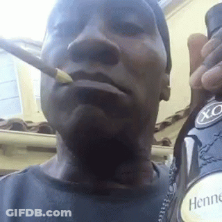 A Man Is Smoking A Cigarette While Holding A Bottle Of Hennessy X.o. GIF
