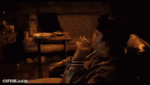 A Man Is Smoking A Cigarette While Sitting On A Couch . GIF