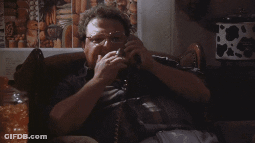 A Man Is Smoking A Cigarette While Talking On A Phone With The Word Excell Behind Him GIF