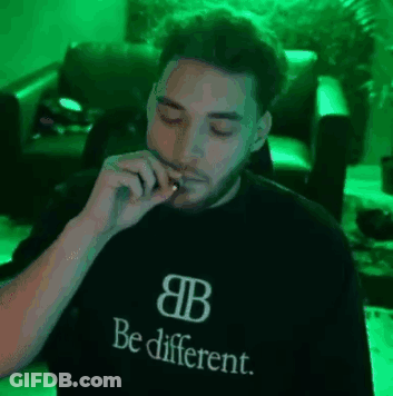 A Man Is Smoking A Cigarette While Wearing A Black Shirt That Says `` Be Different '' . GIF