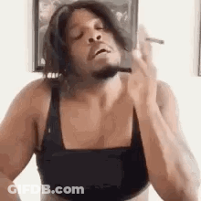 A Man Is Smoking A Cigarette While Wearing A Bra . GIF