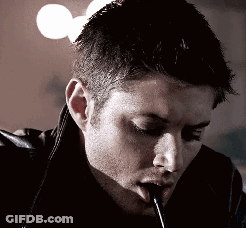 A Man Is Smoking A Cigarette With A Straw In His Mouth . GIF