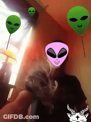 A Man Is Smoking A Cigarette With Alien Faces On His Face GIF