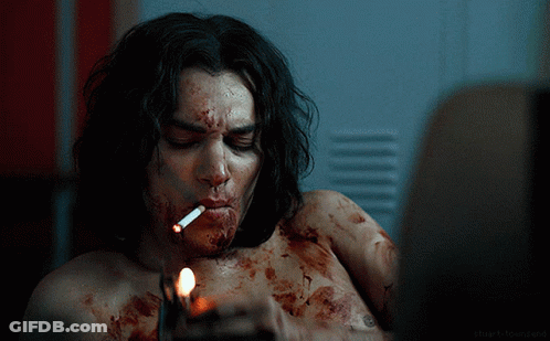 A Man Is Smoking A Cigarette With Blood On His Face GIF