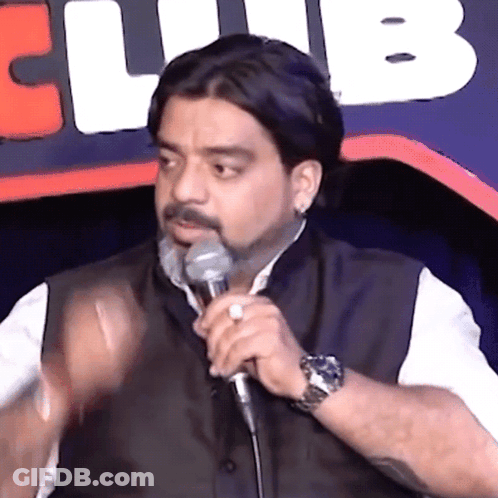 A Man Is Speaking Into A Microphone In Front Of A Club Logo GIF