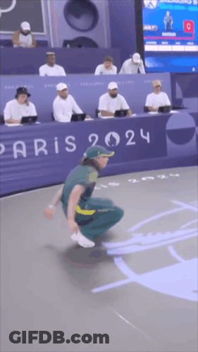 A Man Is Squatting Down In Front Of A Paris Sign GIF