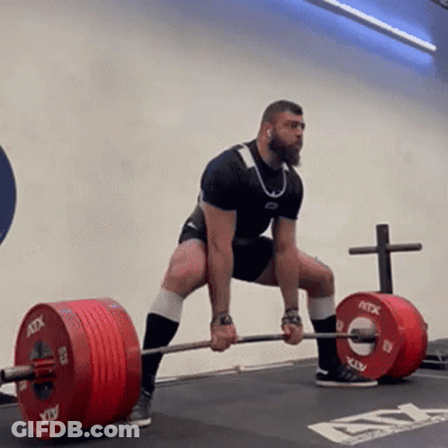 A Man Is Squatting Down While Holding A Barbell . GIF