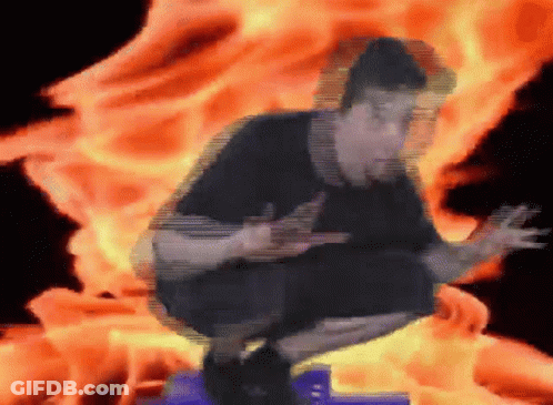 A Man Is Squatting In Front Of A Fire GIF