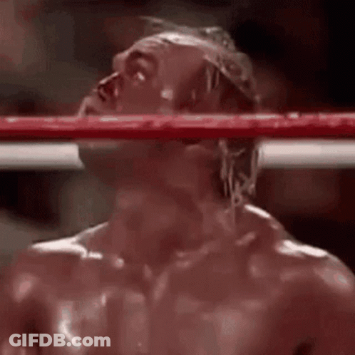 A Man Is Standing In A Boxing Ring With His Head Hanging Over The Ring . GIF