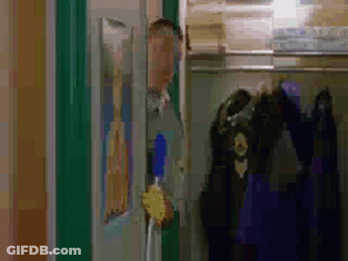 A Man Is Standing In A Closet Holding A Broom And Looking Out The Door . GIF