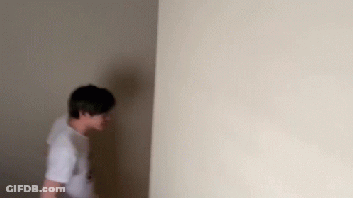 A Man Is Standing In A Corner Of A Room . GIF