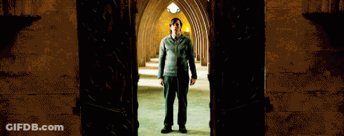 A Man Is Standing In A Dark Hallway With A Door Open GIF