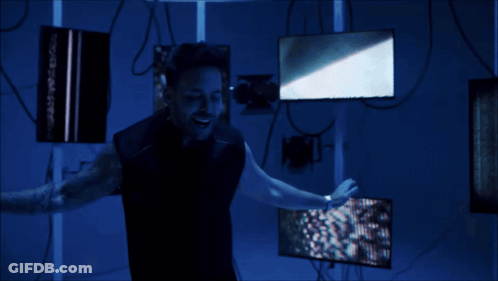 A Man Is Standing In A Dark Room Holding A Light GIF