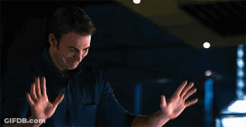 A Man Is Standing In A Dark Room With His Hands Outstretched And Smiling . GIF