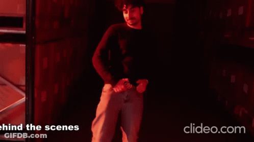 A Man Is Standing In A Dark Room With The Words Behind The Scenes On The Bottom Right GIF