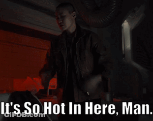 A Man Is Standing In A Dark Room With The Words " It 'S So Hot In Here Man " Above Him GIF