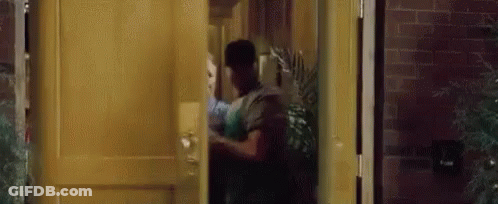 A Man Is Standing In A Doorway Holding A Woman 'S Hand . GIF