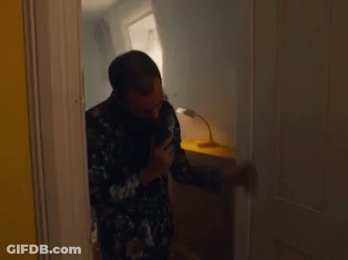 A Man Is Standing In A Doorway Talking On A Phone . GIF