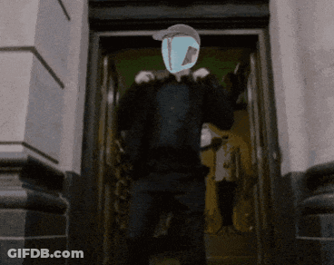 A Man Is Standing In A Doorway With A Mask On His Head GIF