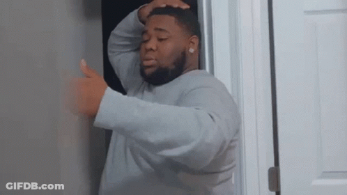 A Man Is Standing In A Doorway With His Hands On His Head . GIF