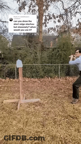 A Man Is Standing In A Field Holding A Hammer And A Bottle Of Water . GIF