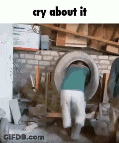 A Man Is Standing In A Garage With A Tire In His Back And The Words Cry About It Above Him GIF