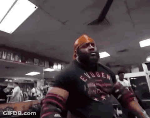 A Man Is Standing In A Gym Wearing A Bandana And A Black Shirt . GIF