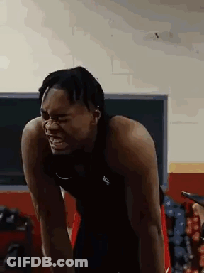 A Man Is Standing In A Gym With His Arms Outstretched And His Mouth Open . GIF