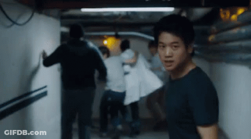 A Man Is Standing In A Hallway With A Group Of People . GIF