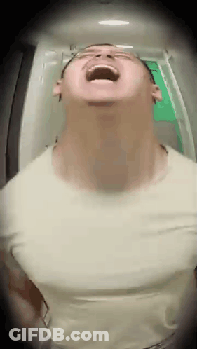 A Man Is Standing In A Hallway With His Mouth Open And Looking Up . GIF